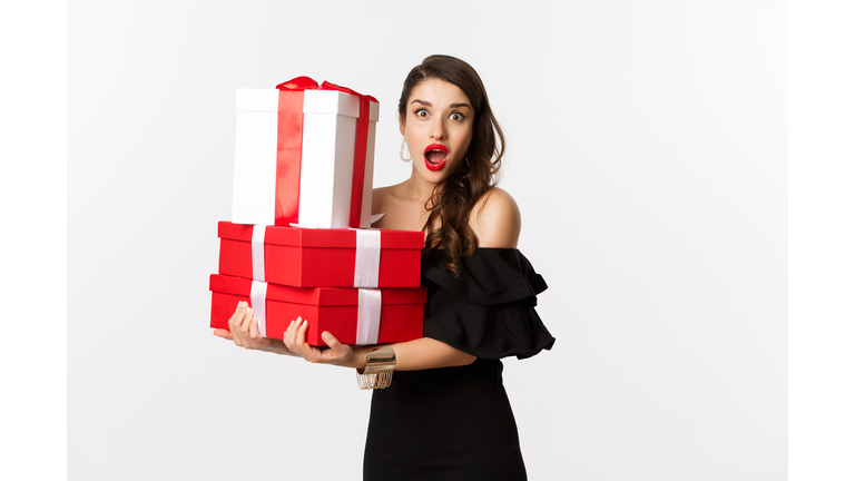 Portrait of young businesswoman holding gift boxes against white background