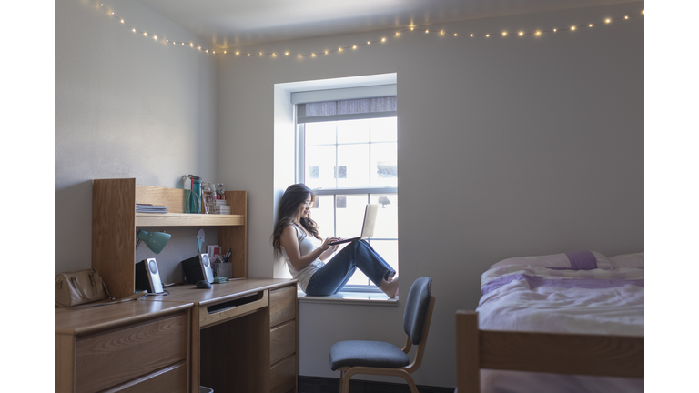 Young woman college student in her dorm room with laptop