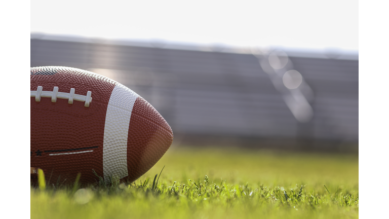 American football on stadium field at school campus.