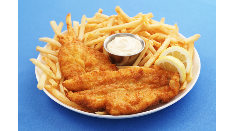 A close up of a fish and chips platter with dipping sauce