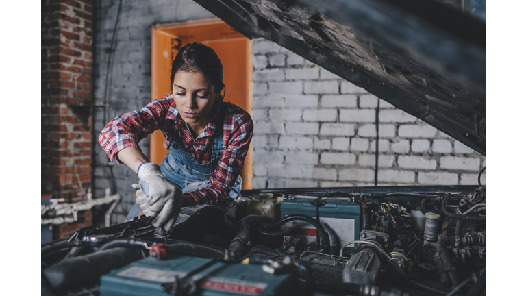 Female mechanic repairing car engine at garage