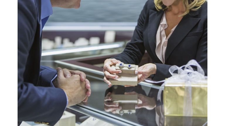 Saleswoman helping man shop for jewelry