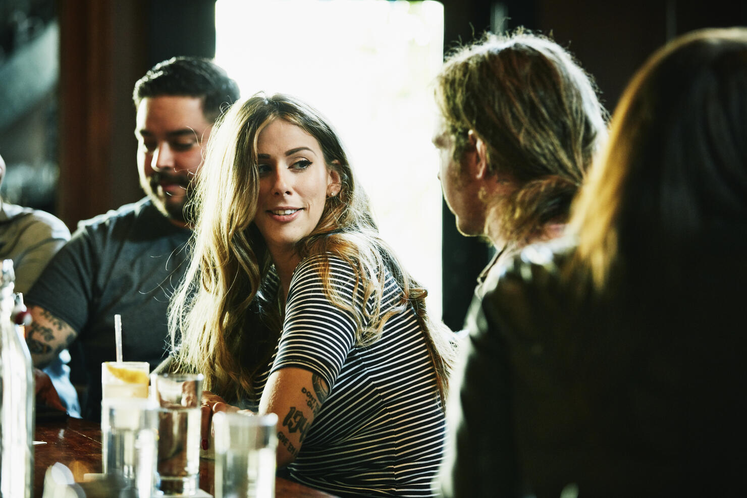 Smiling woman hanging out with friend while having drinks in bar