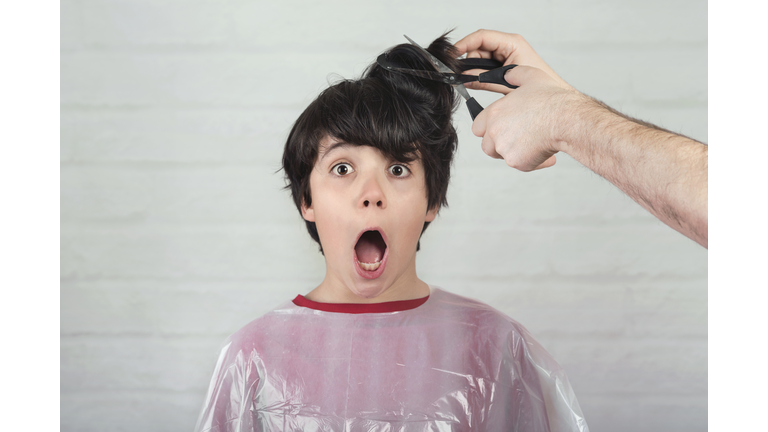 Portrait Of Shocked Boy With Mouth Open Getting Hair Cut