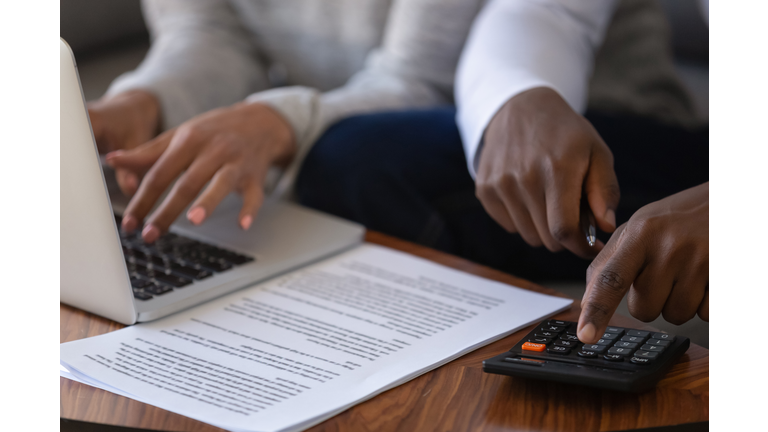 Close up of multiracial couple calculating finances paying online