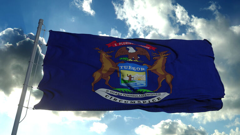 Michigan flag on a flagpole waving in the wind, blue sky background. 3d rendering