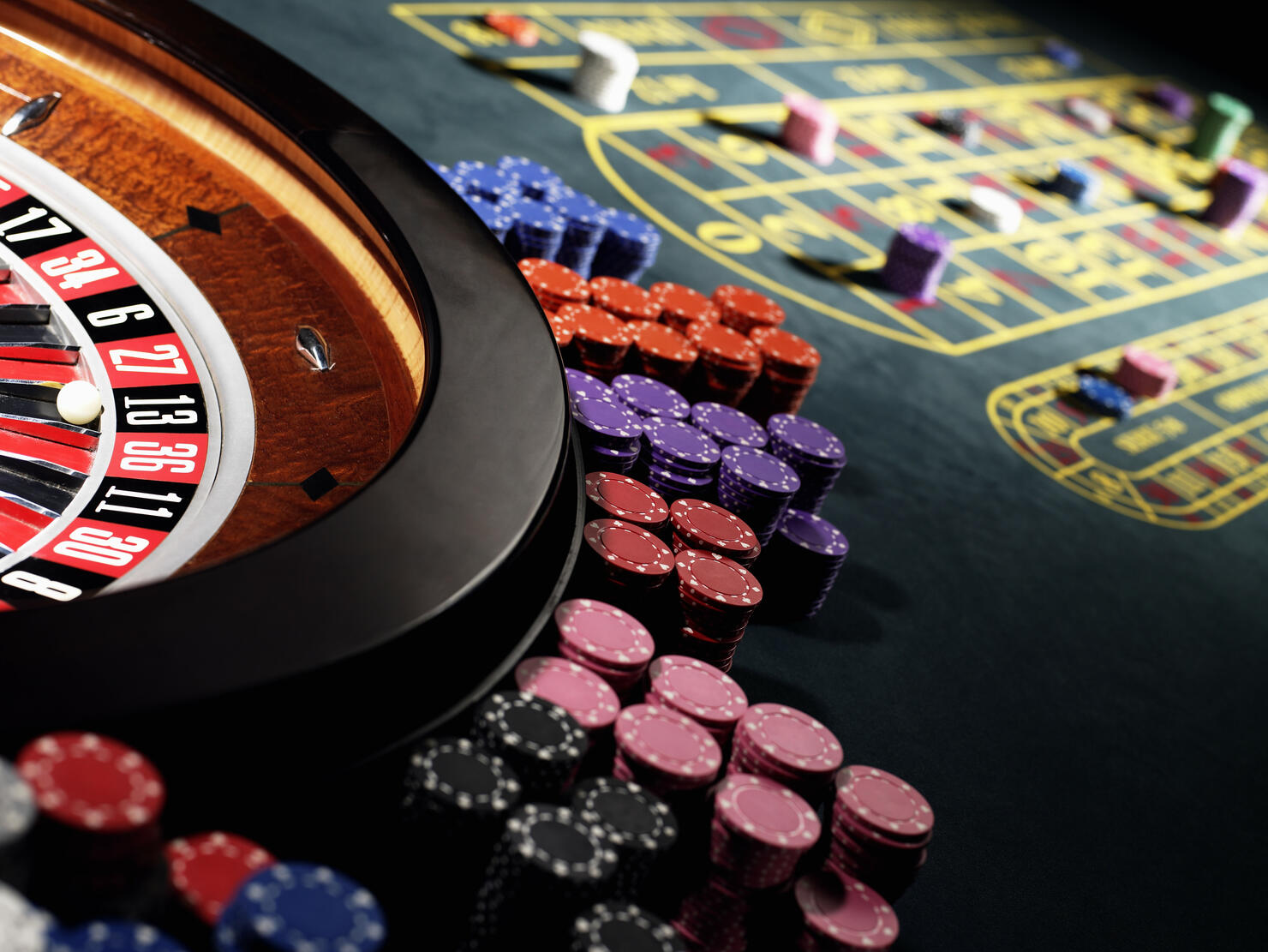 Gambling chips stacked around roulette wheel on gaming table