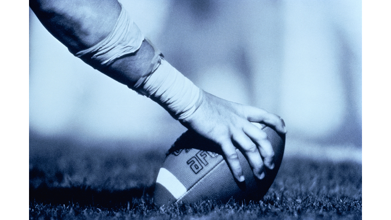 American football player's hand on ball, close-up (B&W)