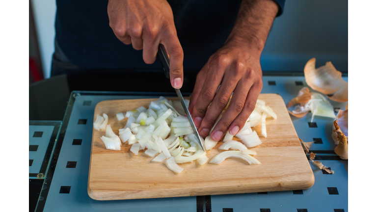 Hands of a man chopping onions