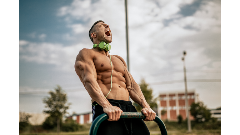 Young man showing his muscles in the local park