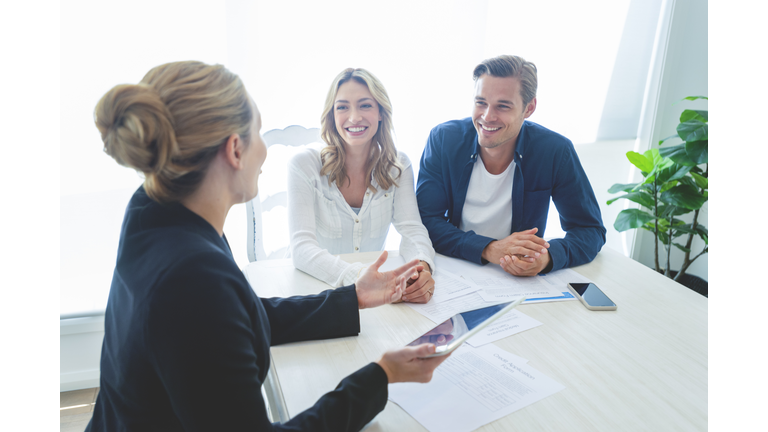 Insurance agent with couple looking through documents.