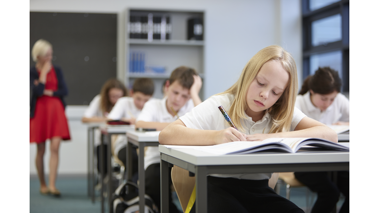 Female teacher watching class doing educational exam