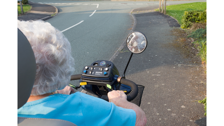 Rear close up view of elderly woman using Mobility scooter to travel