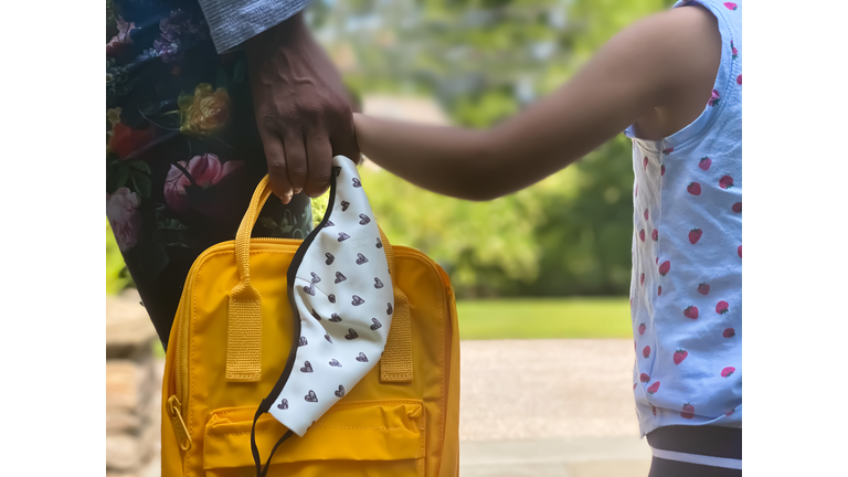 mixed-race toddler & her african-american mother await school bus for first day of preschool while holding hands
