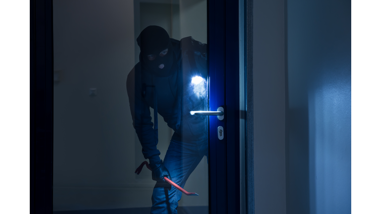 Thief With Flashlight Trying To Break Door