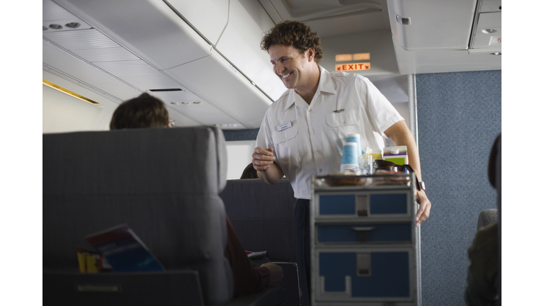 Steward serving passengers on airplane