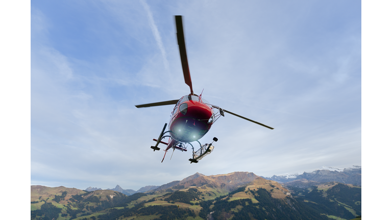 red rescue helicopter landing on mountain