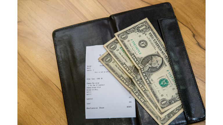 Cash on bill paper. US dollar banknote tips in leather black bill reciept.