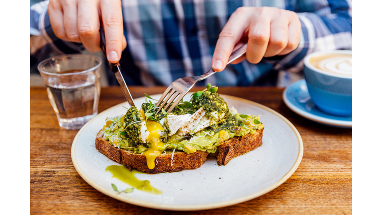 Man eating avocado toast with poached egg, close up