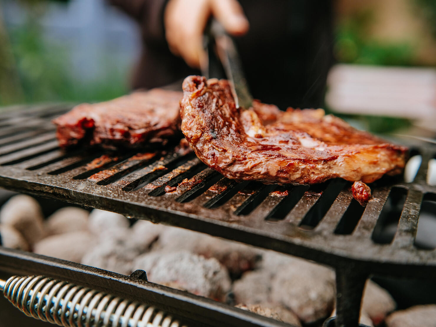 Woman doing BBQ Steaks on a flame grill.