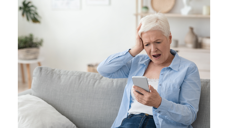 Mobile Scams Concept. Shocked Senior Woman Looking At Smartphone Screen In Frustration