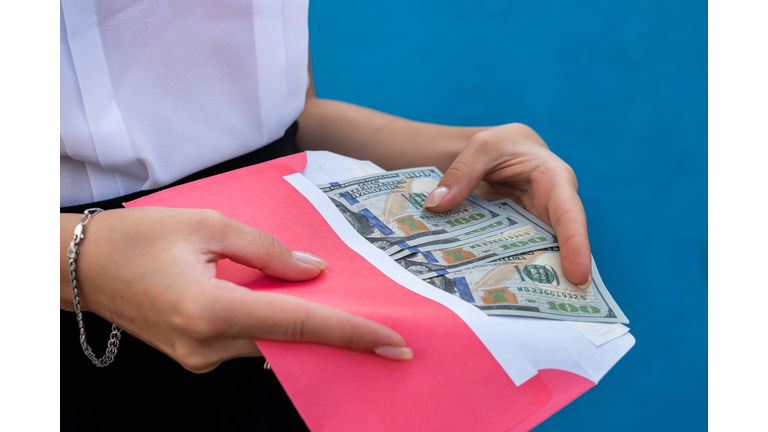 female hands in handcuffs holding an envelope with dollars