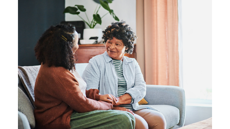 Shot of an elderly woman relaxing with her daughter on the sofa at home