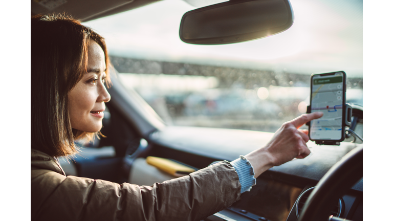 Young pretty Asian woman using Gps navigation in the car