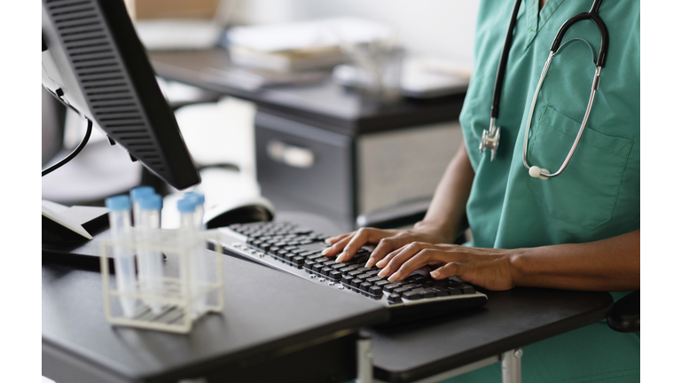 Mixed race nurse working at computer