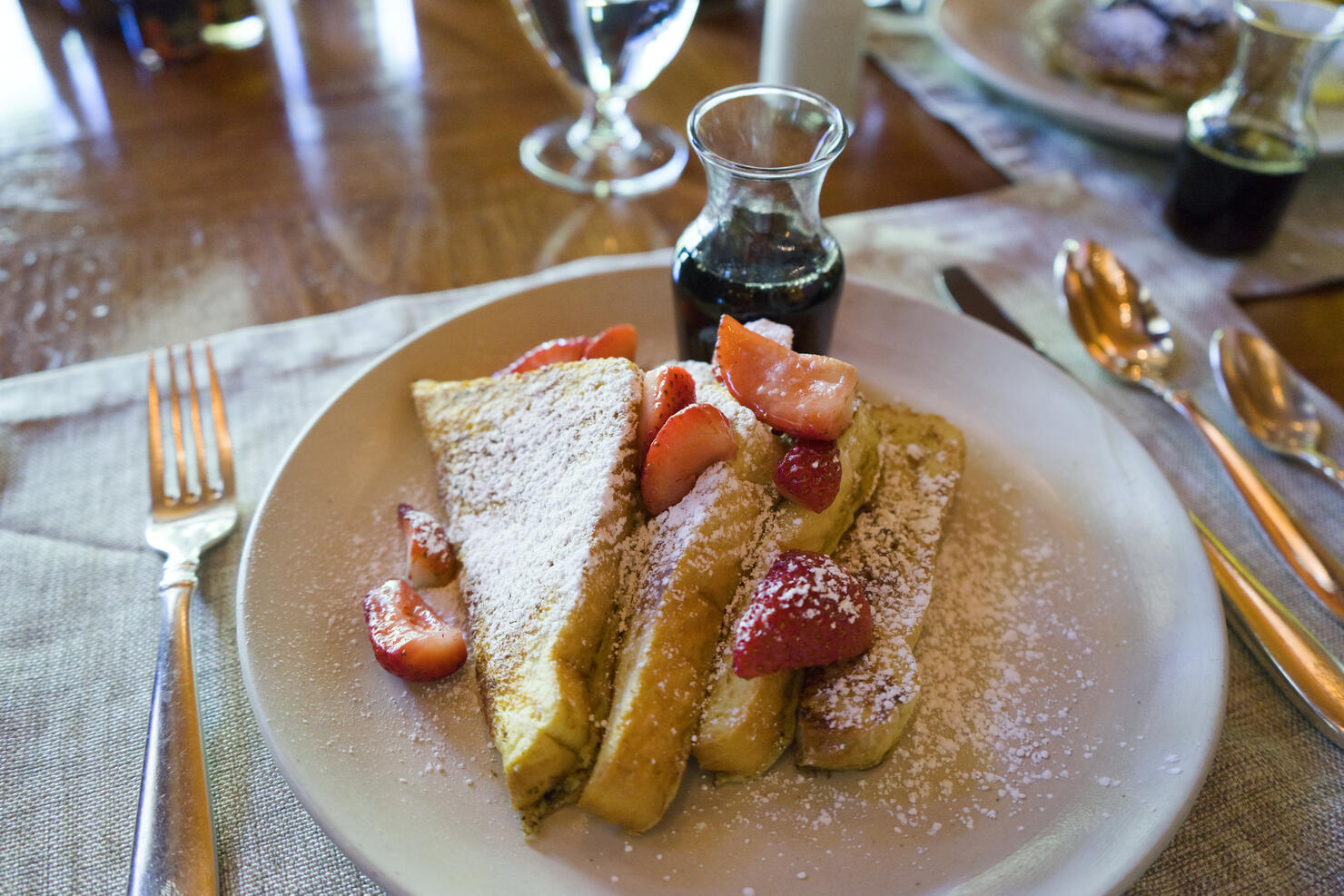 French toast with strawberries, powdered sugar and maple syrup