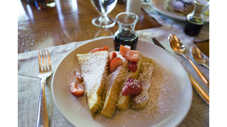 French toast with strawberries, powdered sugar and maple syrup