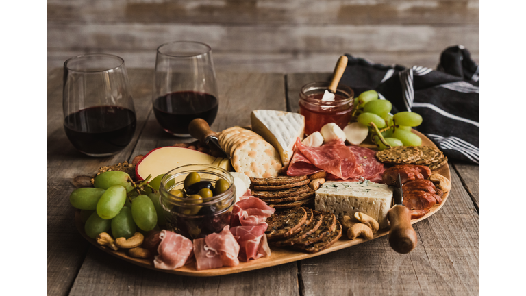 Close up of charcuterie board and glasses of wine on wooden table.