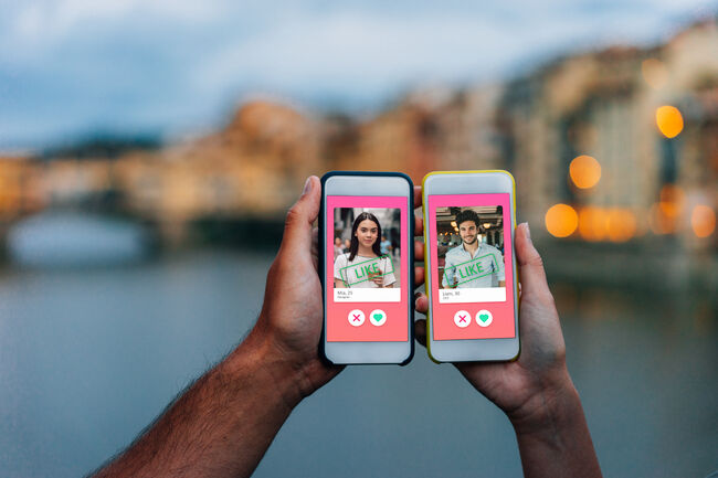 Conceptual image of two hands holding smart phones with an online dating app on the screen