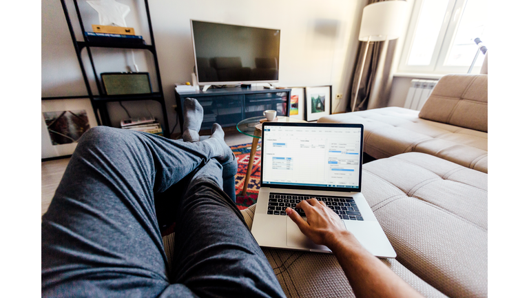 Personal perspective point of view of a man working on laptop in the living room at home
