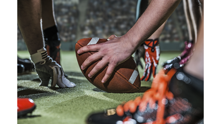 American football held by player on field