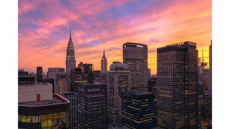Beautiful colorful sunset over midtown Manhattan, viewed from a unique angle from a rooftop in NYC. Seeing the Empire State Building, Chrysler Building, MetLife Building.