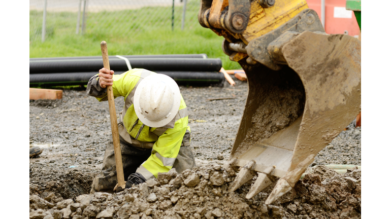 Construction worker digging dirt out with the help of crane