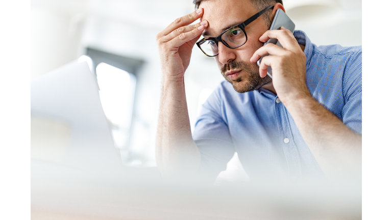 Worried businessman having problems while working on wireless technology at home.