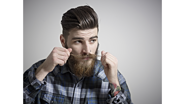 Portrait of young man twisting his moustache.