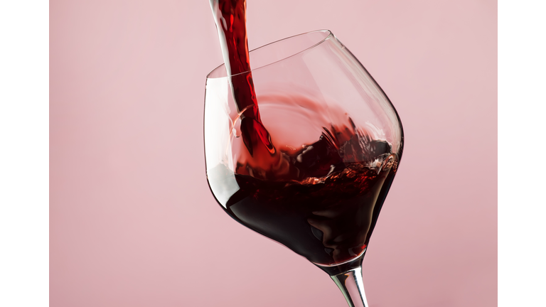 French dry red wine, pours into glass, trendy pink background