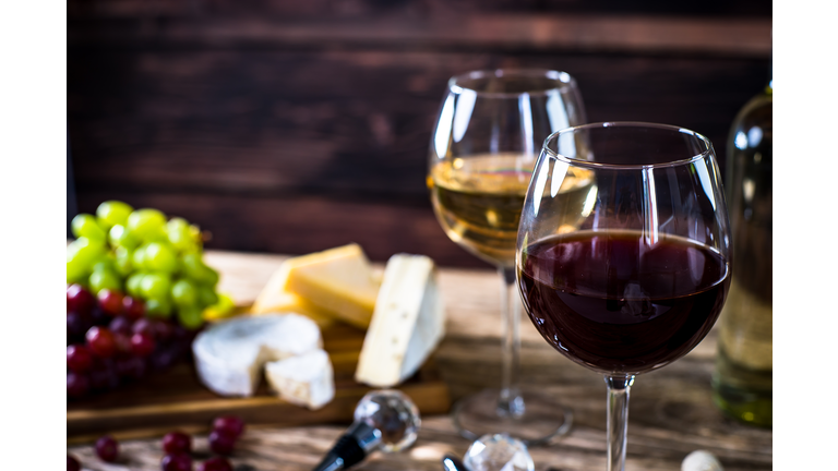 Glass of  wine, cheeses and grapes on brown wooden background