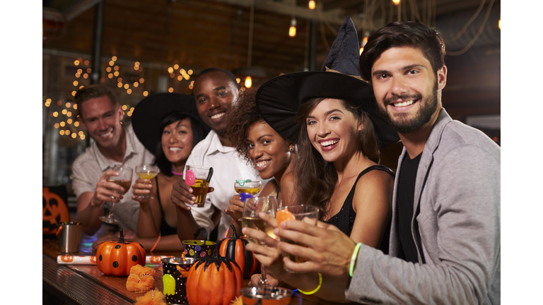 Friends enjoying a Halloween party at a bar look to camera