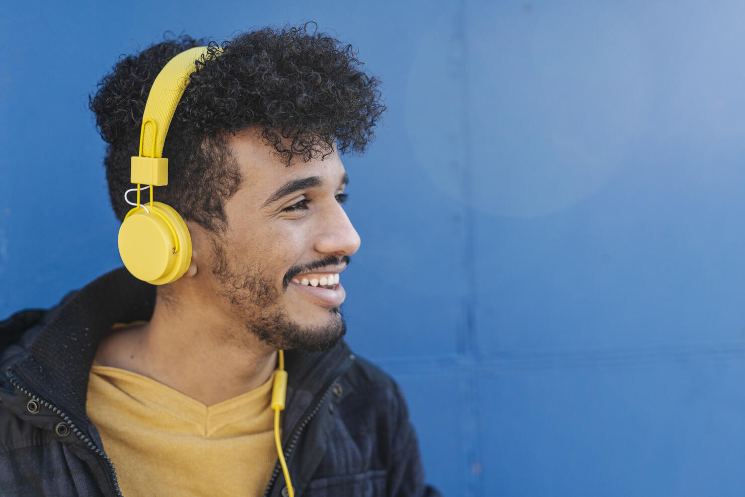 Portrait of young man smiling and listening to music with headphones