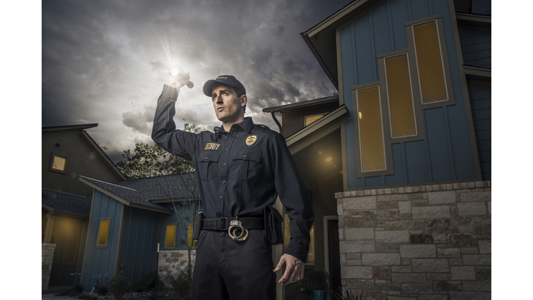 Caucasian police officer shining flashlight near house