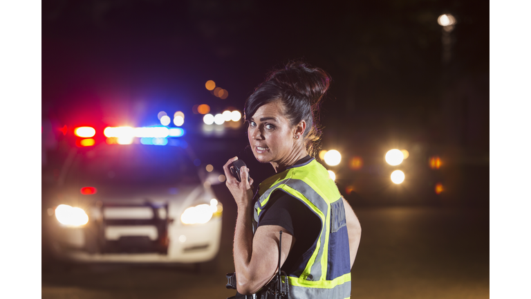 Female police officer at night, talking into radio