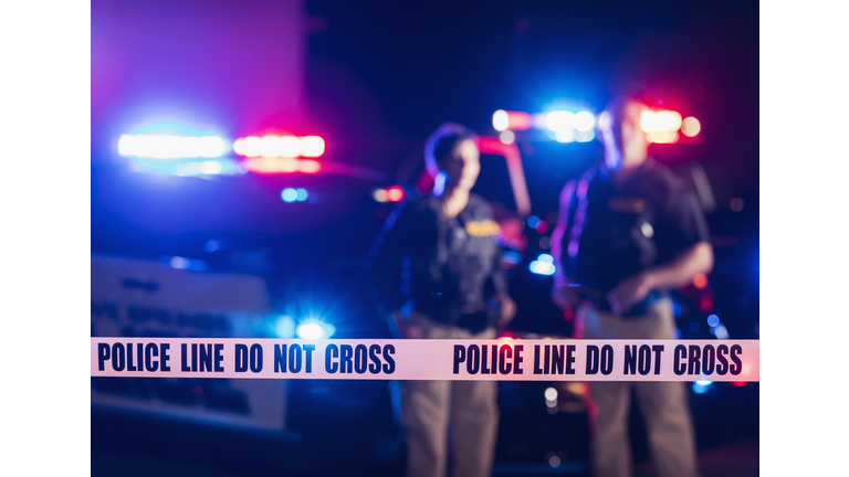 Two police officers standing in front of patrol cars