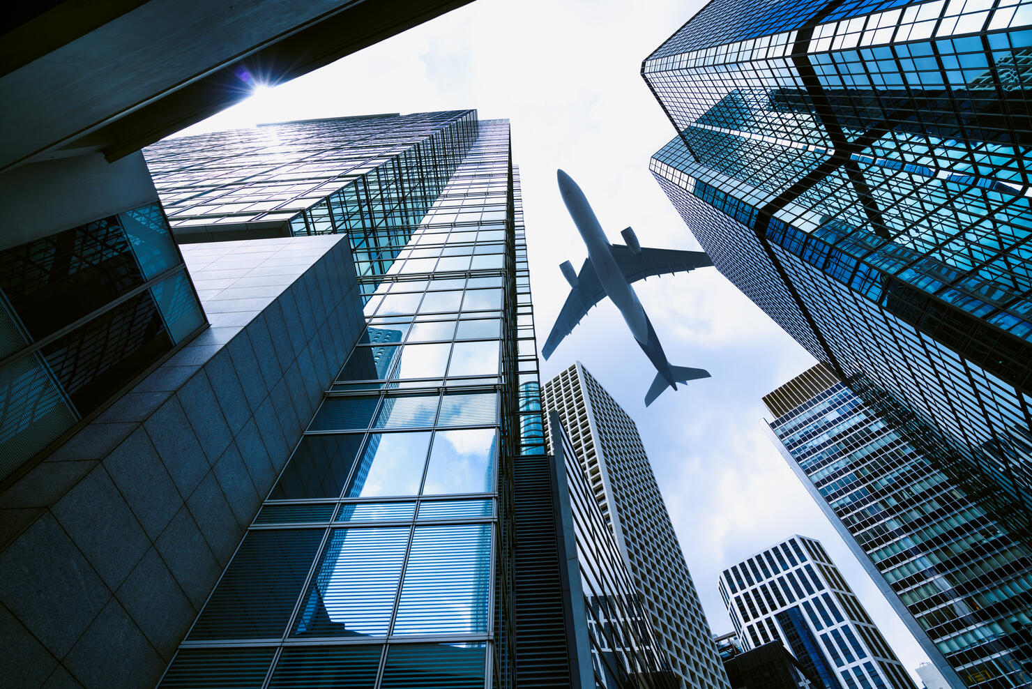 A plane flying over modern office buildings in central Hong Kong.