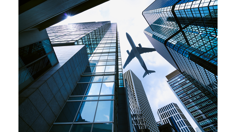 A plane flying over modern office buildings in central Hong Kong.