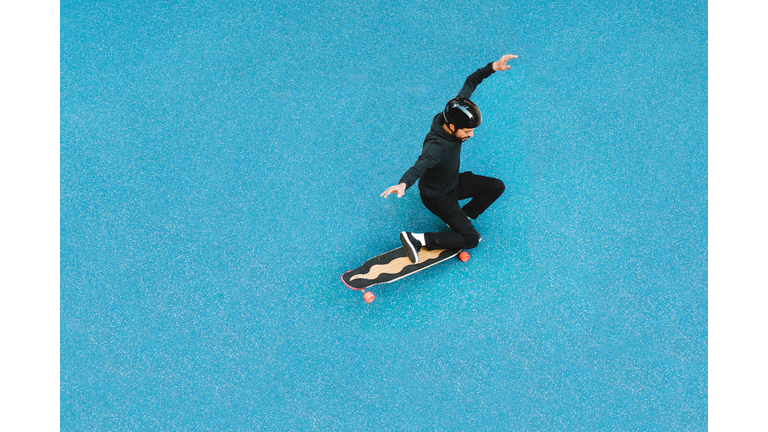 High angle view of man skateboarding on blue floor at skateboard park