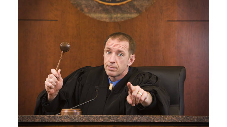 Upset judge swinging gavel and pointing